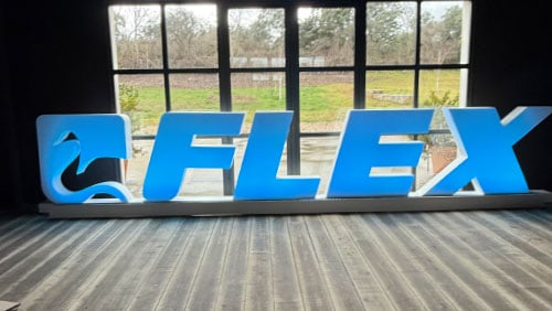 Letras corpóreas azules del logotipo FLEX, con el isotipo recortado, apoyadas antes de su instalación