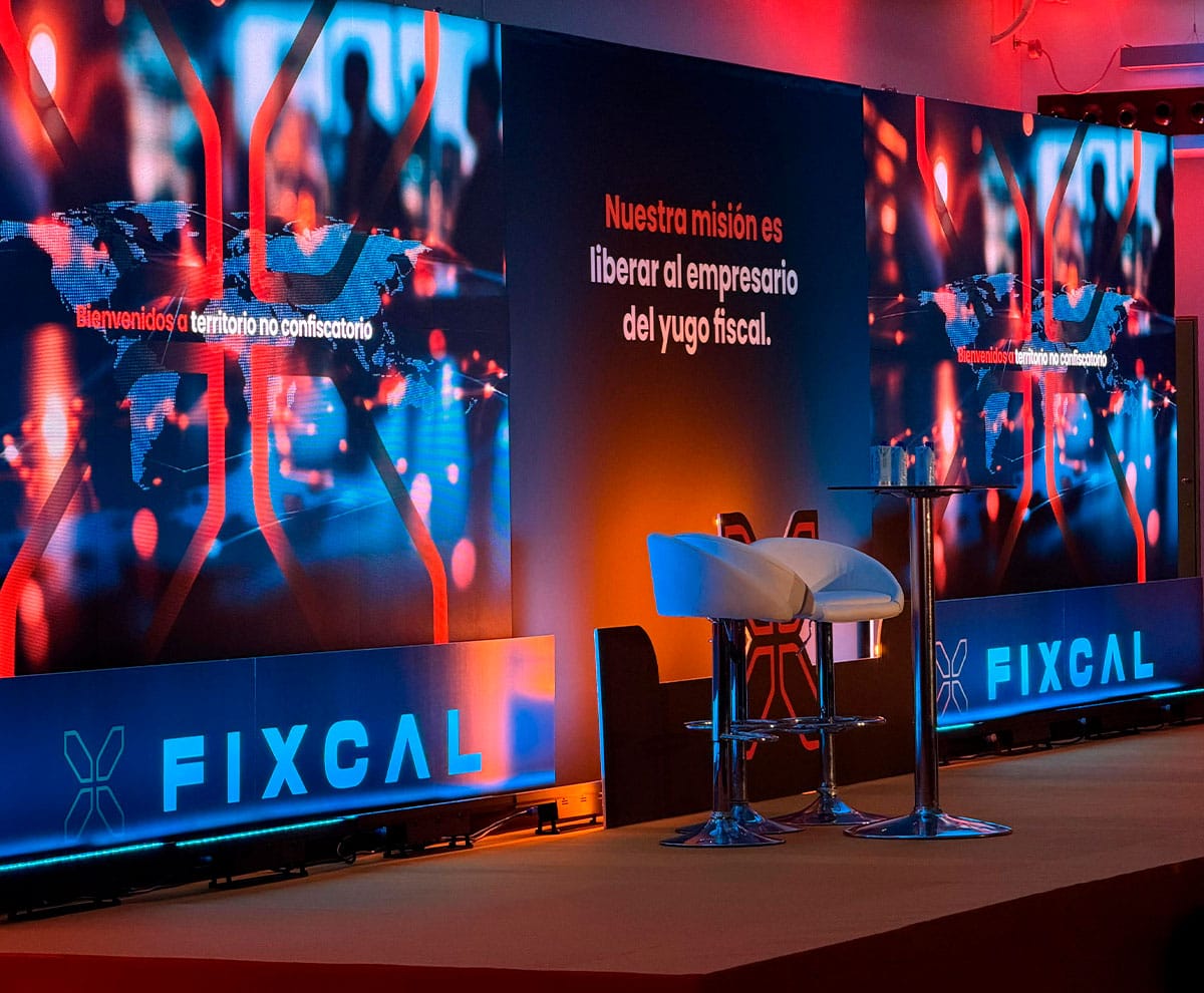 Escenario moderno con pantallas digitales y mobiliario para eventos corporativos.